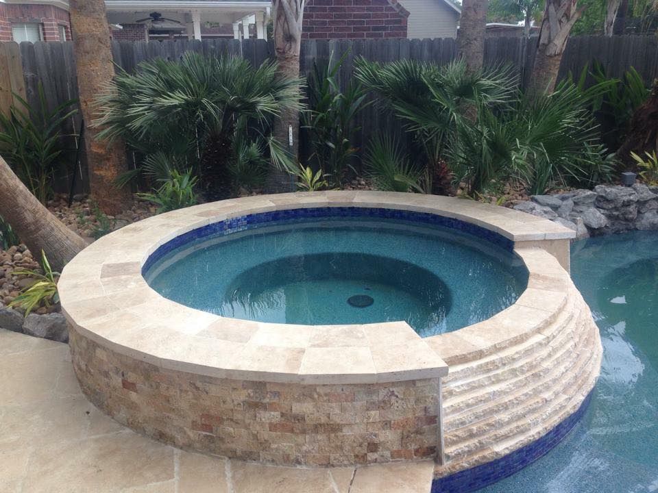 A hot tub is sitting next to a swimming pool surrounded by palm trees.