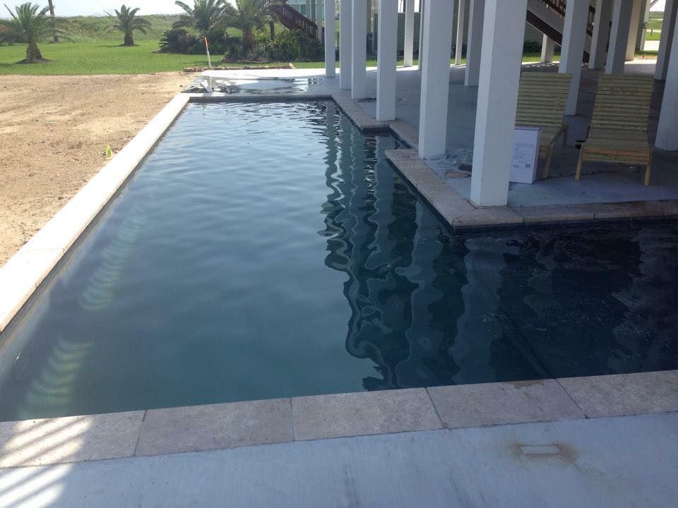A large swimming pool surrounded by white pillars and chairs