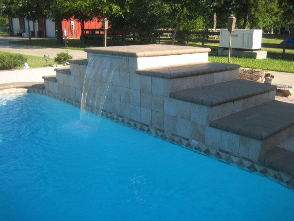 A swimming pool with stairs and a waterfall in the middle
