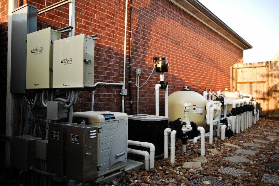 A brick building with a lot of pipes and electrical equipment on the side.