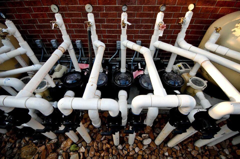 A bunch of pipes are lined up against a brick wall