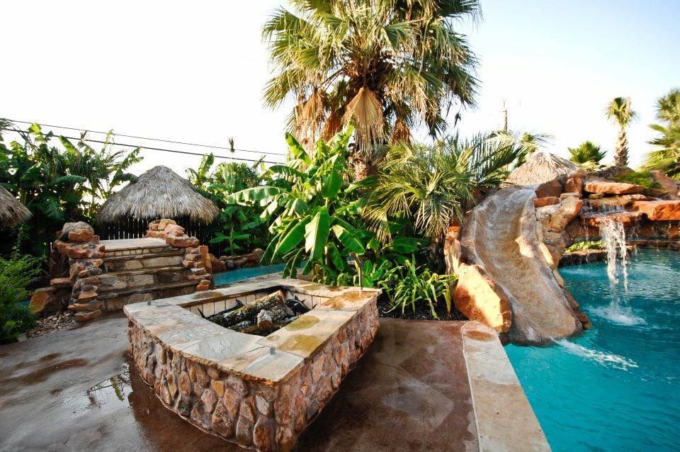 A swimming pool with a water slide and a fire pit