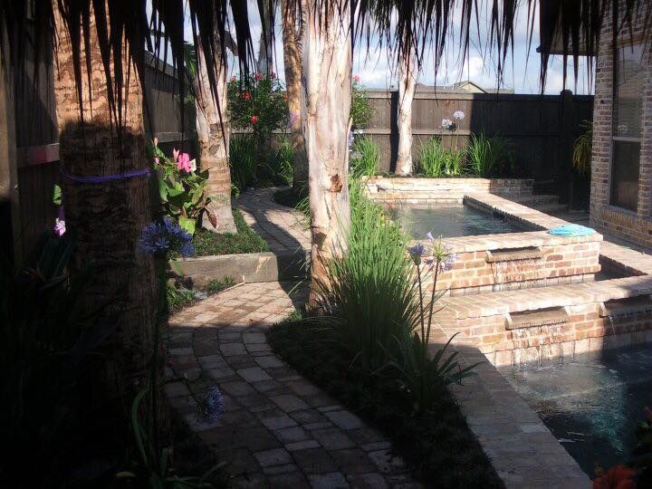 A brick walkway leads to a swimming pool surrounded by palm trees
