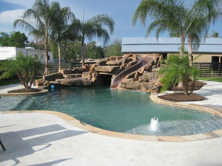 A large swimming pool with a water slide and palm trees
