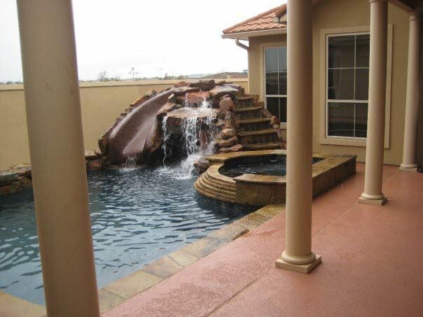 A house with a pool and a waterfall in the backyard