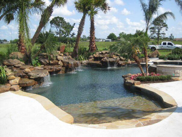 A large swimming pool surrounded by palm trees and rocks