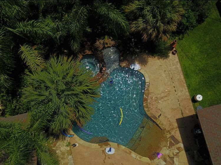 An aerial view of a large swimming pool surrounded by palm trees.