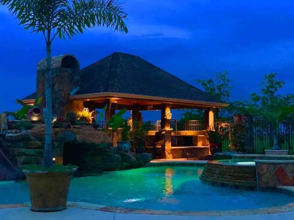 A large swimming pool with a gazebo in the background at night