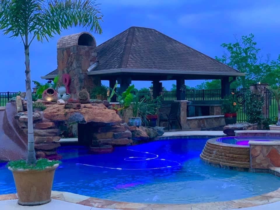 A large swimming pool with a slide and a gazebo in the background