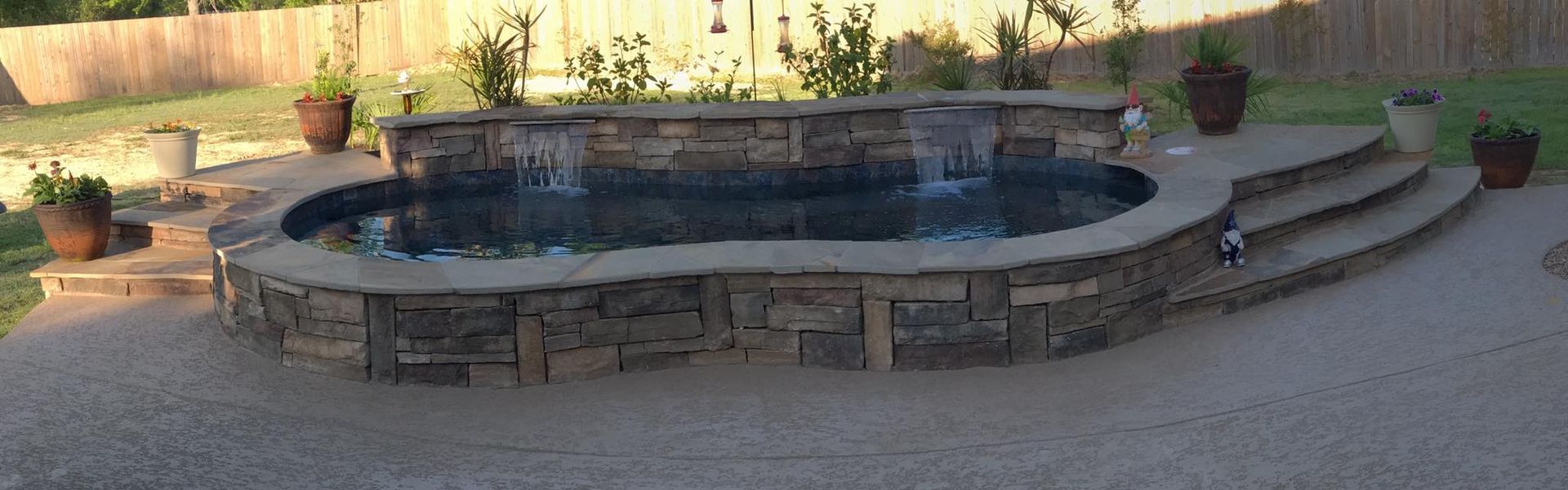 A large swimming pool with a waterfall in the backyard.