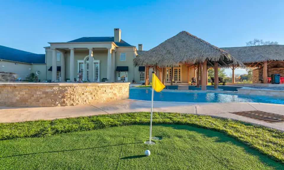 There is a golf course in front of a large house.