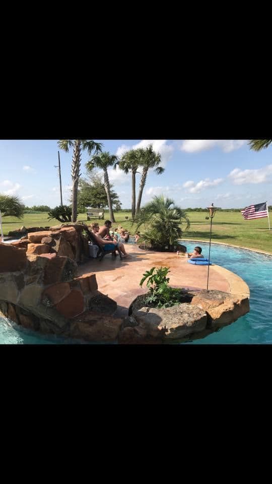 A group of people are sitting on the edge of a swimming pool.