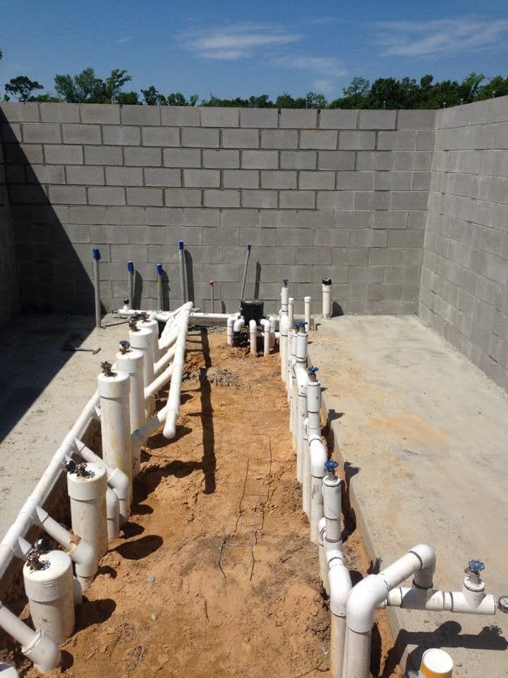 A bunch of white pipes are lined up in the dirt