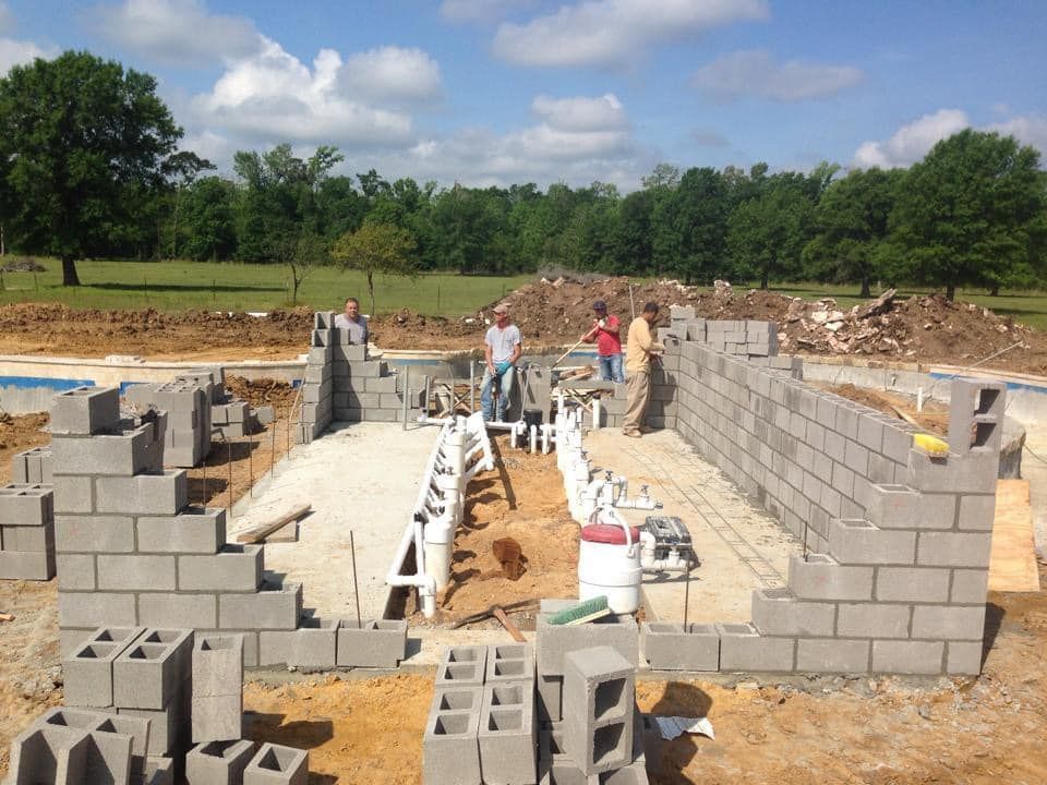 A group of construction workers are working on a brick wall