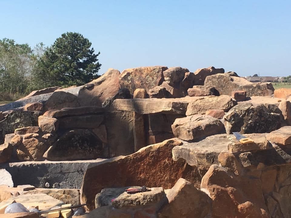A large pile of rocks with trees in the background