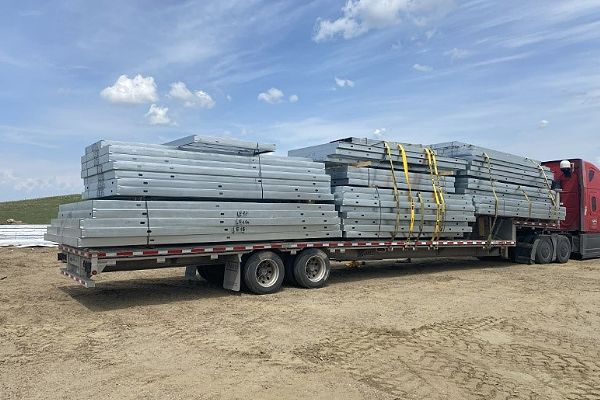 A semi-truck is carrying a stack of scaffolding on a trailer.