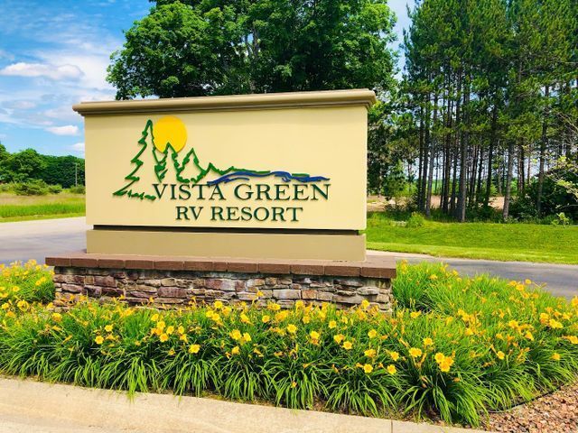 a vista green rv resort sign surrounded by flowers