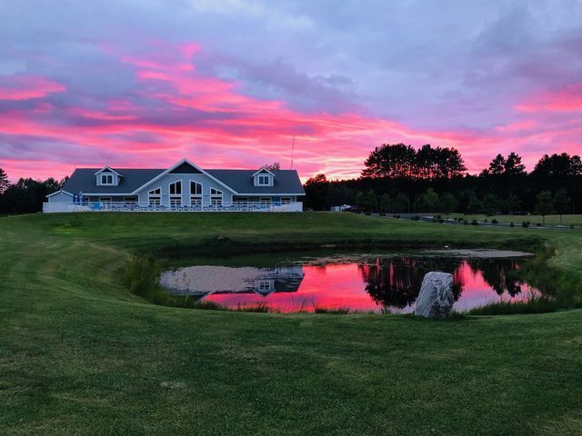 a house with a pond in front of it at sunset