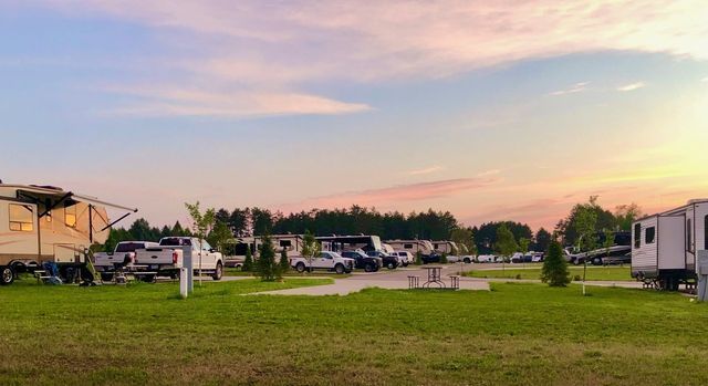 a row of rvs parked in a grassy field at a campground .