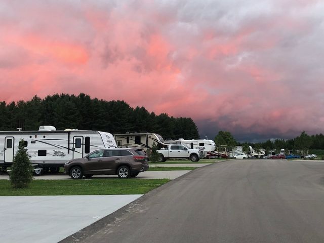 a row of rvs parked in a parking lot with a sunset in the background .