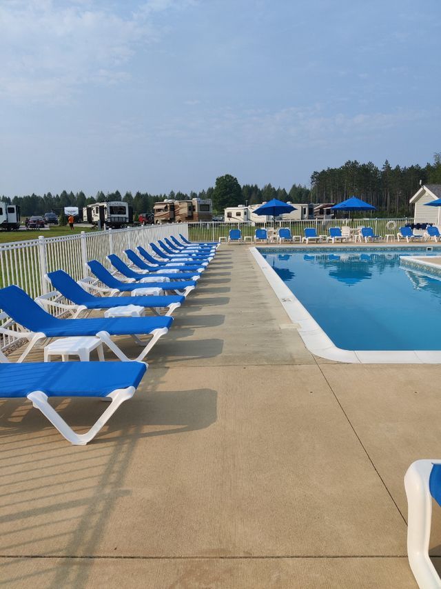 a row of blue lounge chairs next to a swimming pool