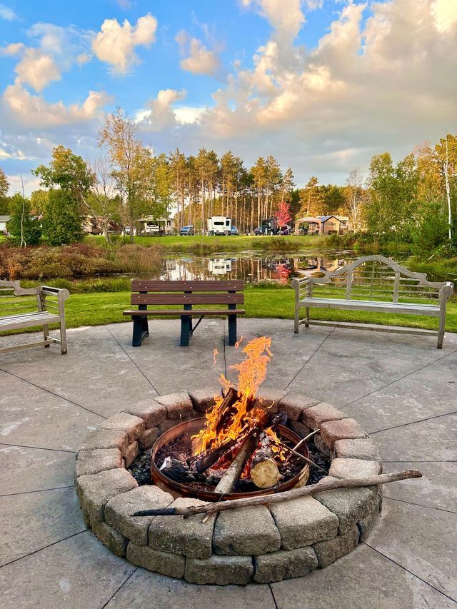 a fire pit in a park with a bench in the background .