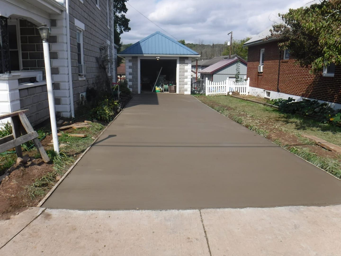 A concrete driveway leading to a garage with a blue roof