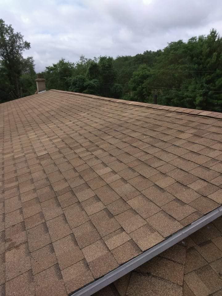 A roof with a lot of shingles and trees in the background.