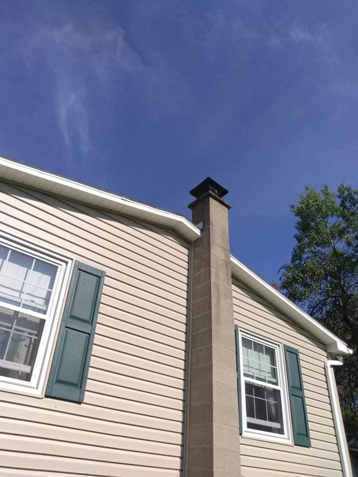 A house with a chimney on the side of it and a blue sky in the background.