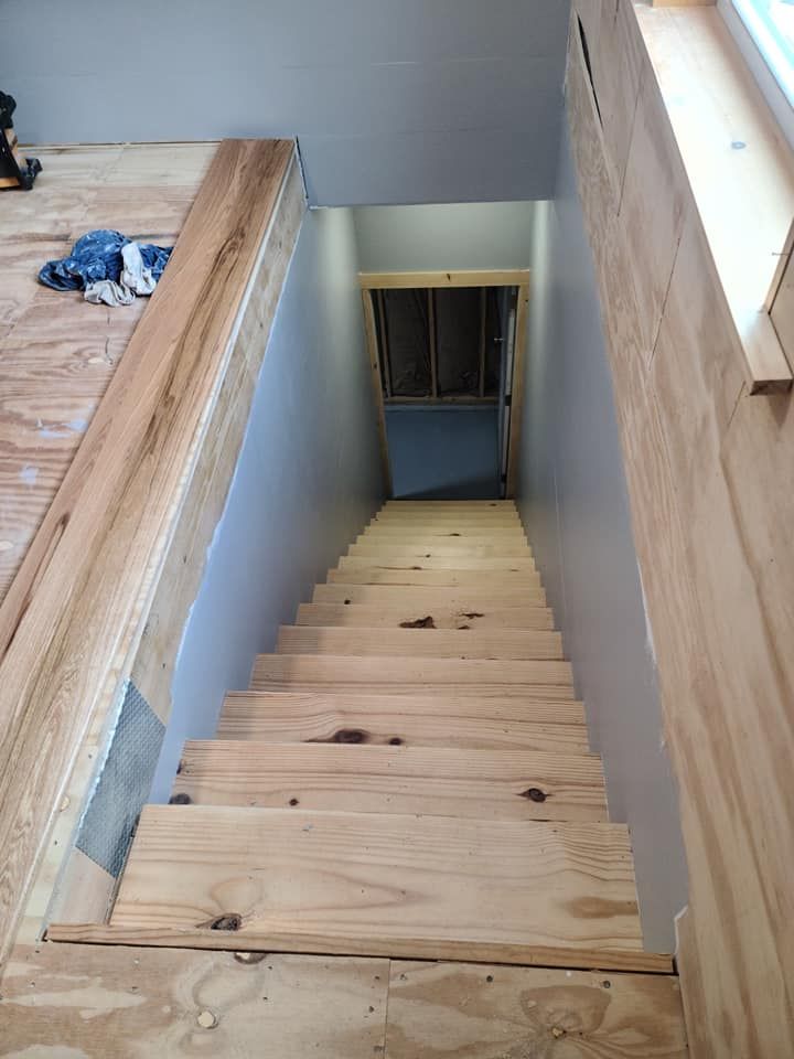 A wooden staircase leading up to a basement under construction.