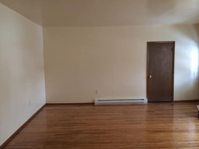 An empty living room with hardwood floors and white walls