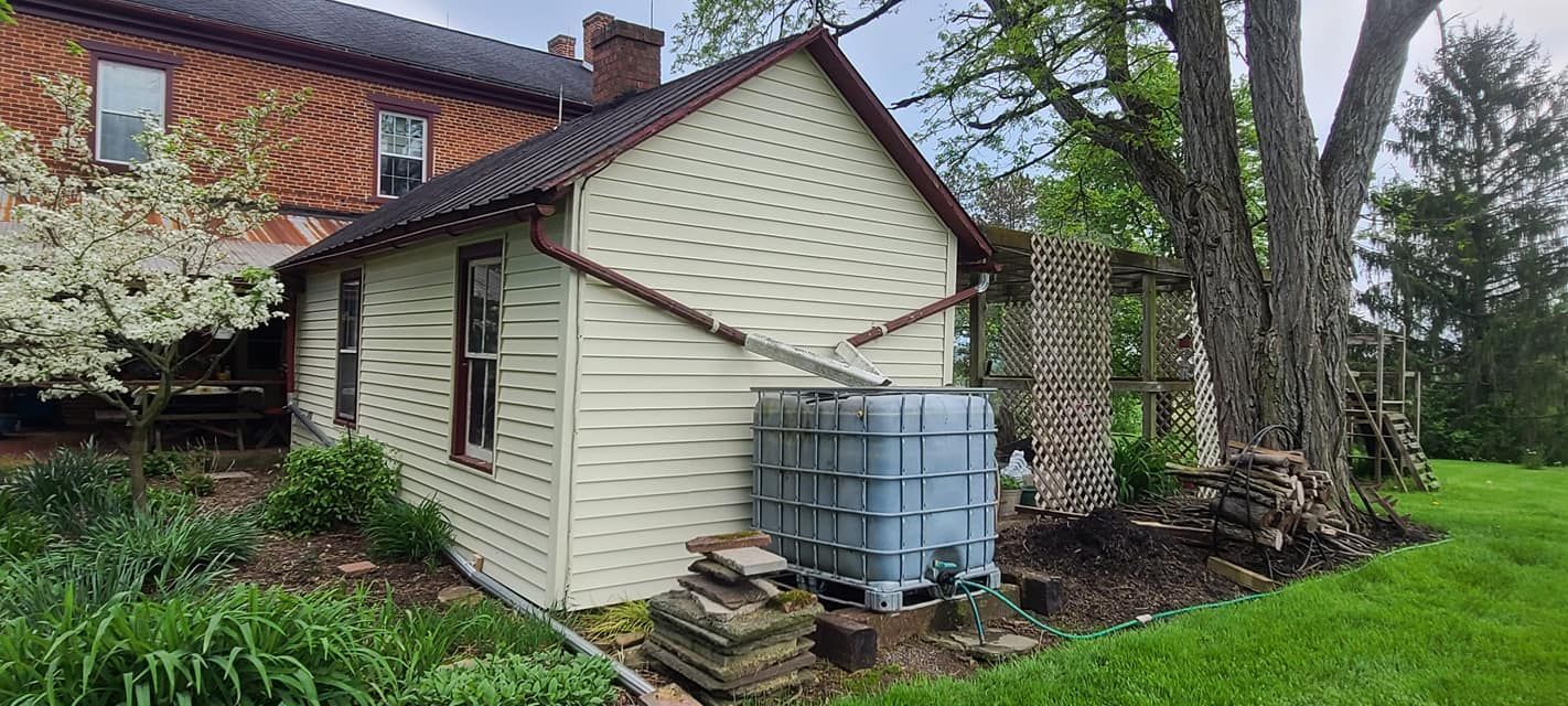 A small house with a water tank in the backyard.