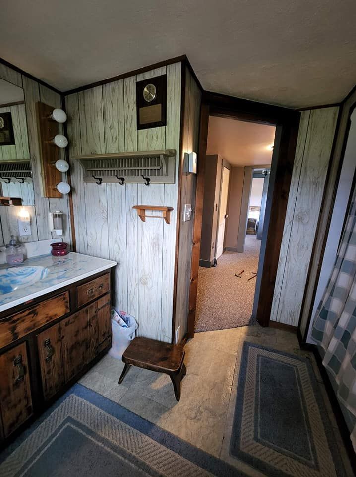 A bathroom with a sink , mirror , and stool.