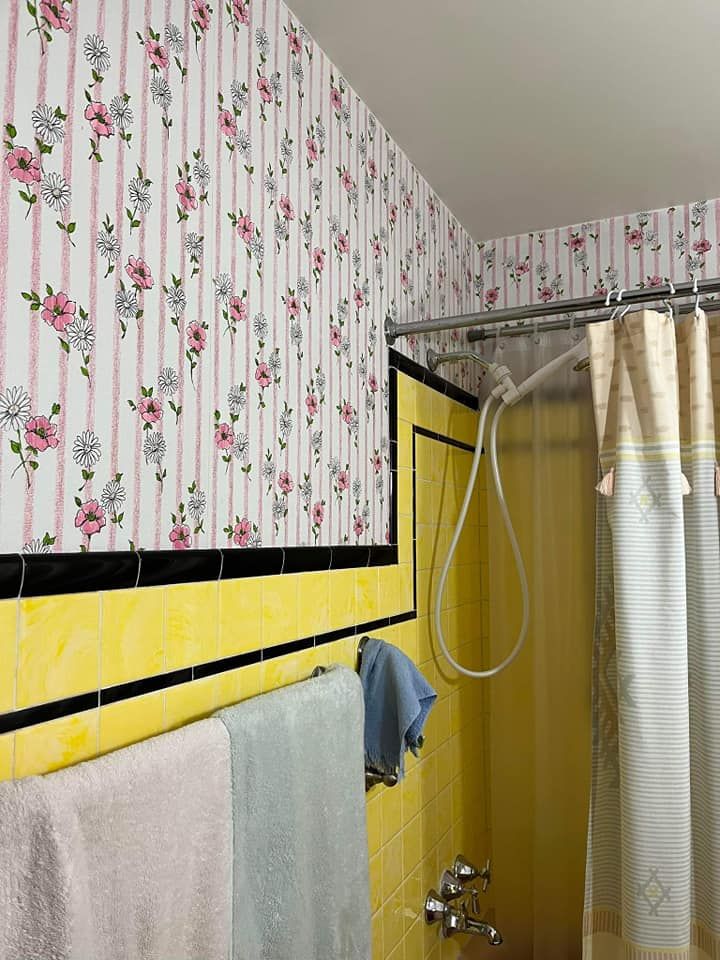 A bathroom with floral wallpaper and a shower curtain
