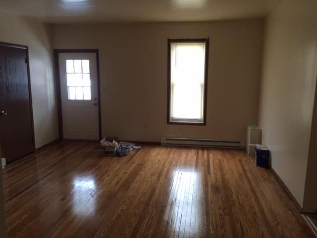 An empty living room with hardwood floors and a window.