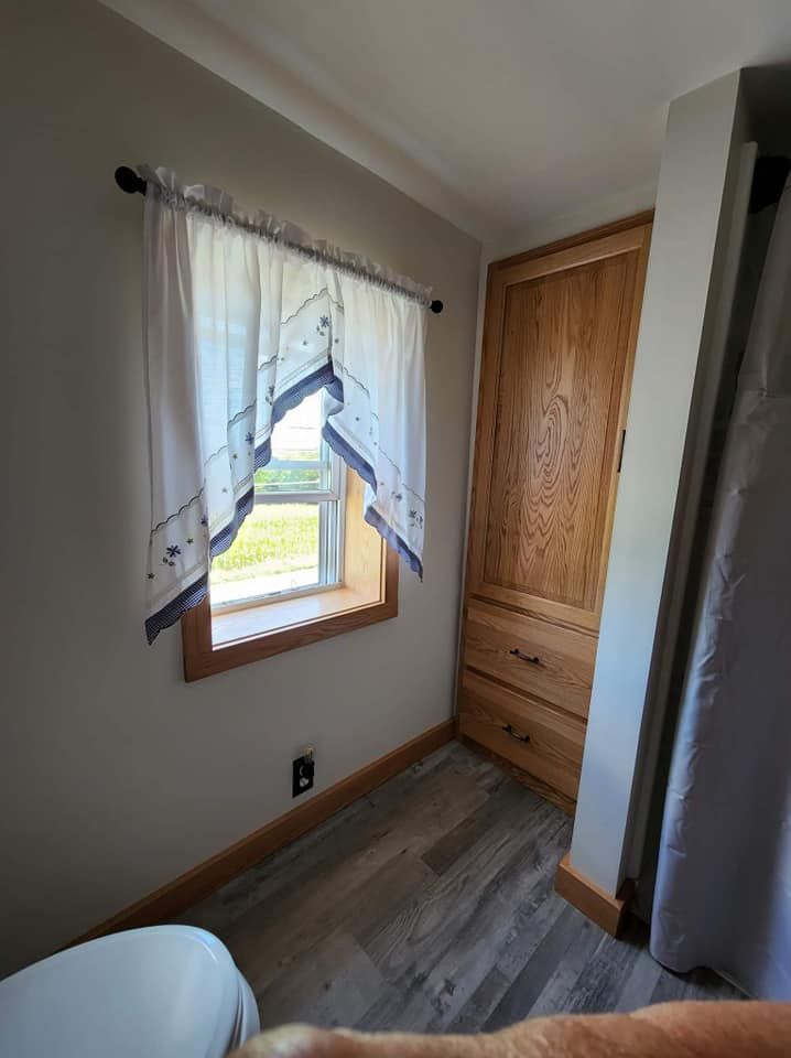 A bathroom with a toilet , window and closet.