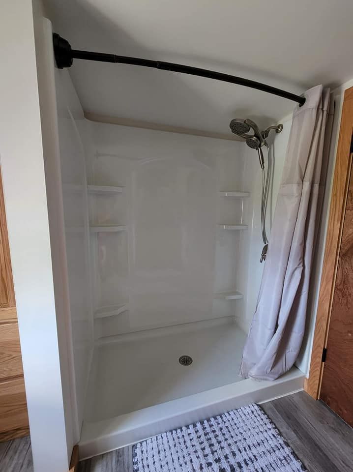 A shower stall with a shower head and a curtain in a bathroom.