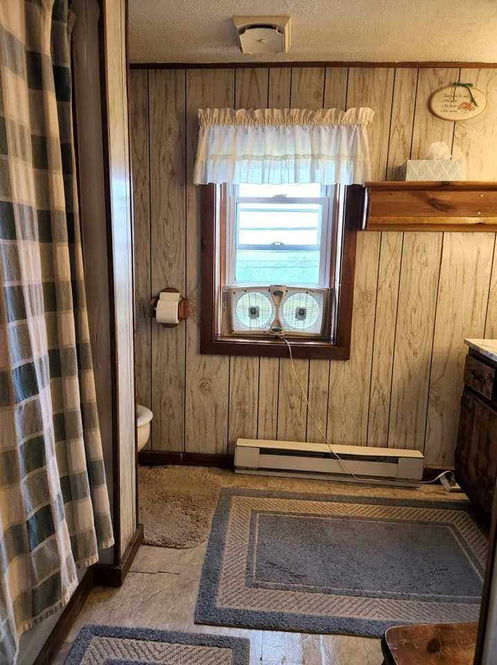 A bathroom with wood paneling and a window with two fans on it.