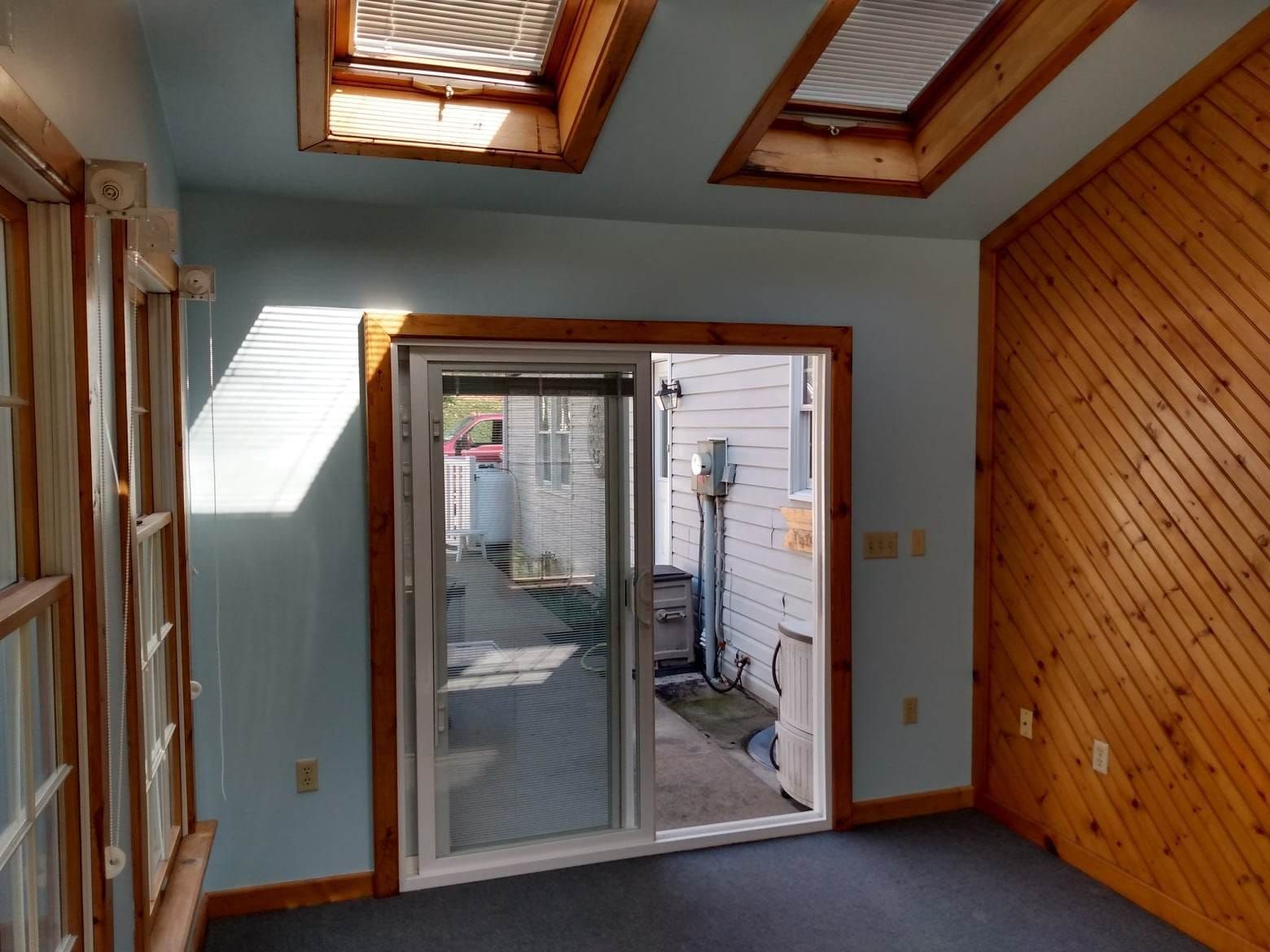 An empty room with a sliding glass door and skylights
