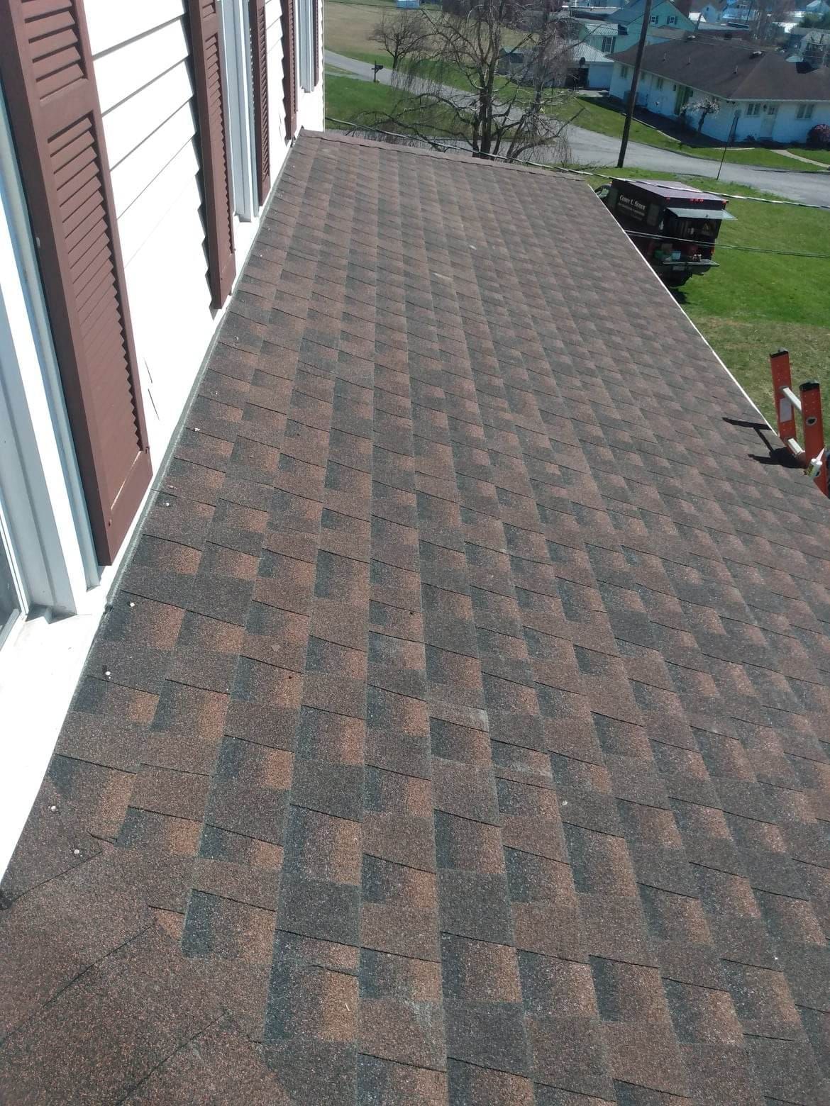 A roof with shingles on it is sitting on top of a house.