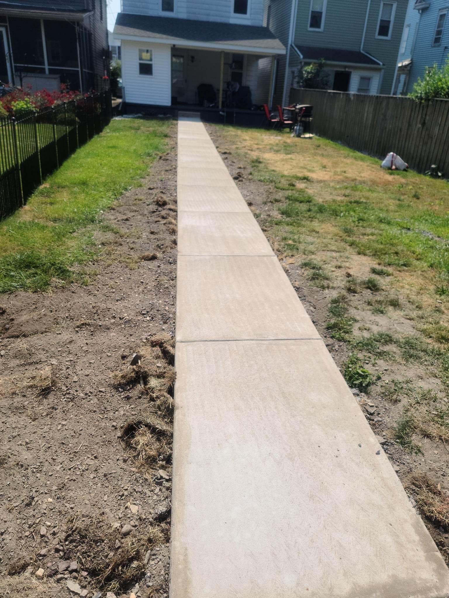 A concrete walkway leading to a house in the backyard.