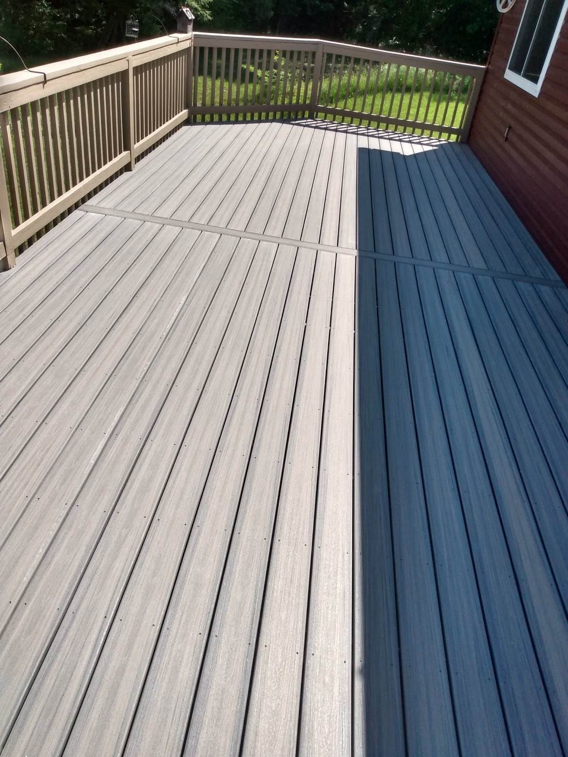 A gray deck with a wooden railing and a bench.