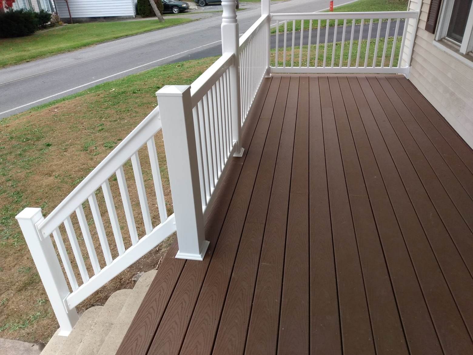 A brown deck with a white railing and stairs