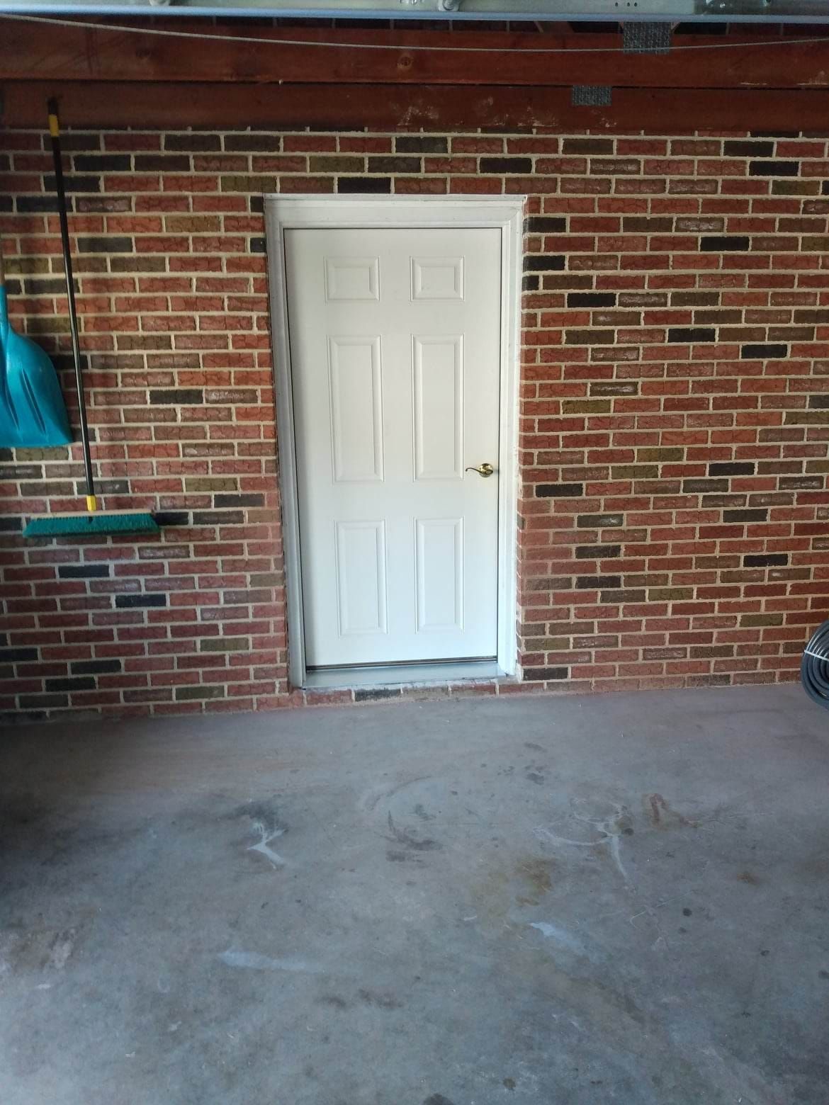 A garage with a brick wall and a white door.