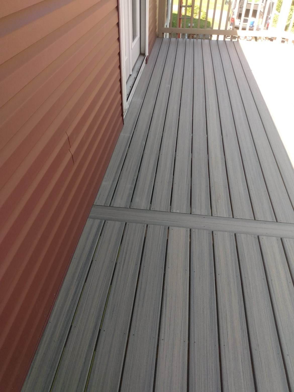 A gray deck with a red siding on the side of a house.