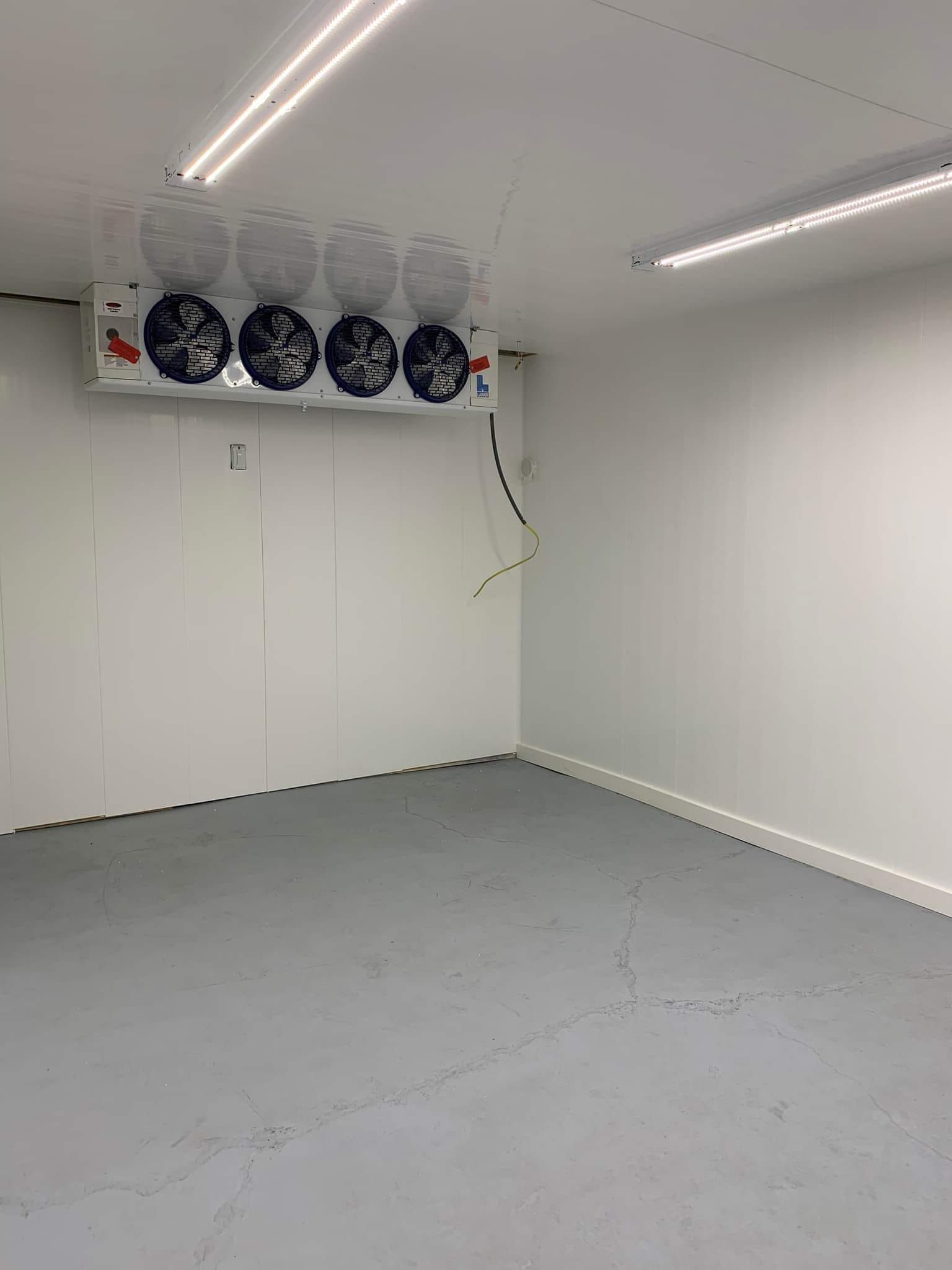 An empty room with a ceiling fan hanging from the ceiling.