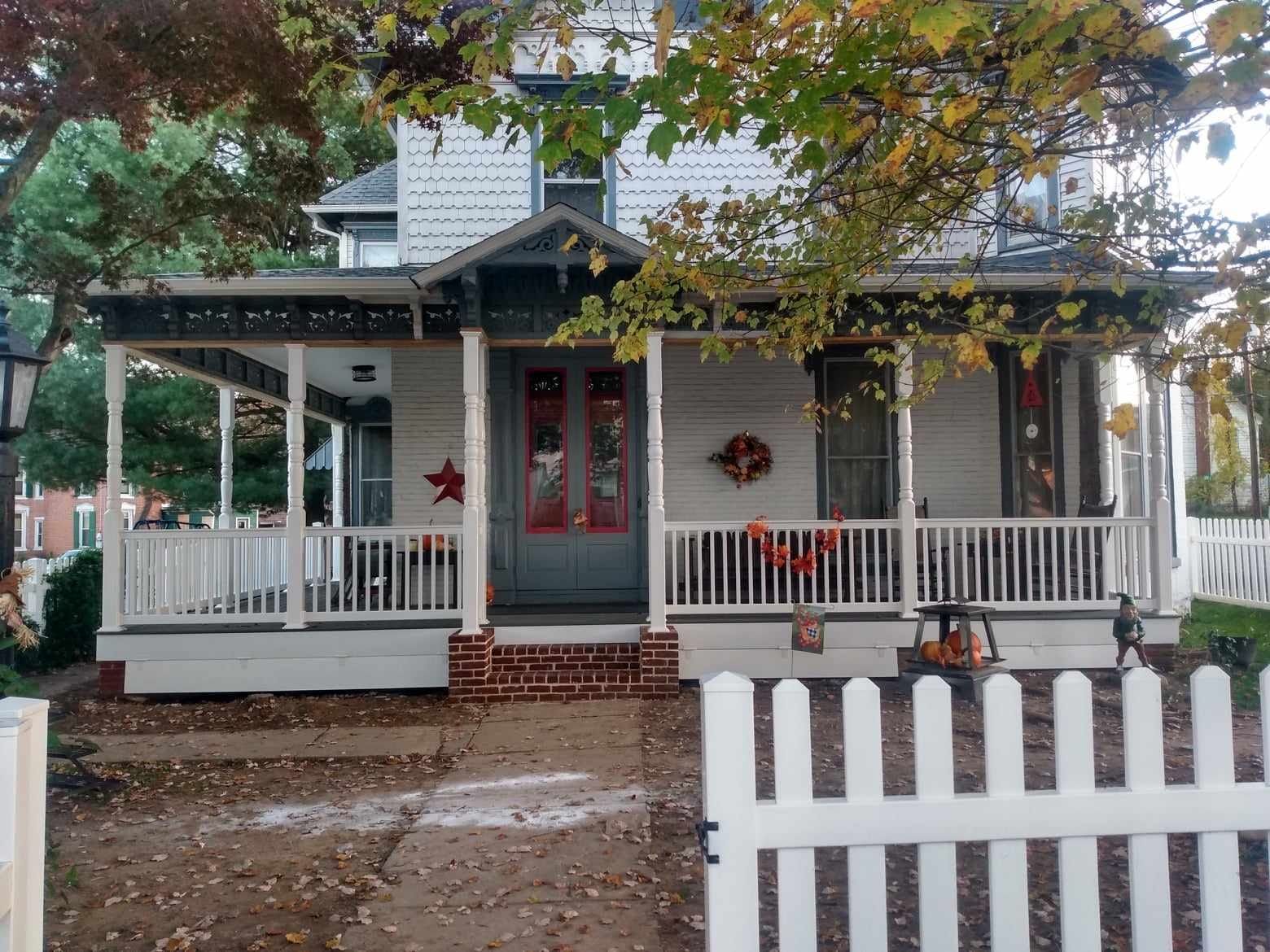 A white house with a porch and a white picket fence