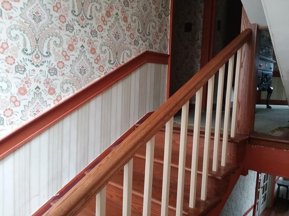 A staircase with a wooden railing and floral wallpaper on the wall