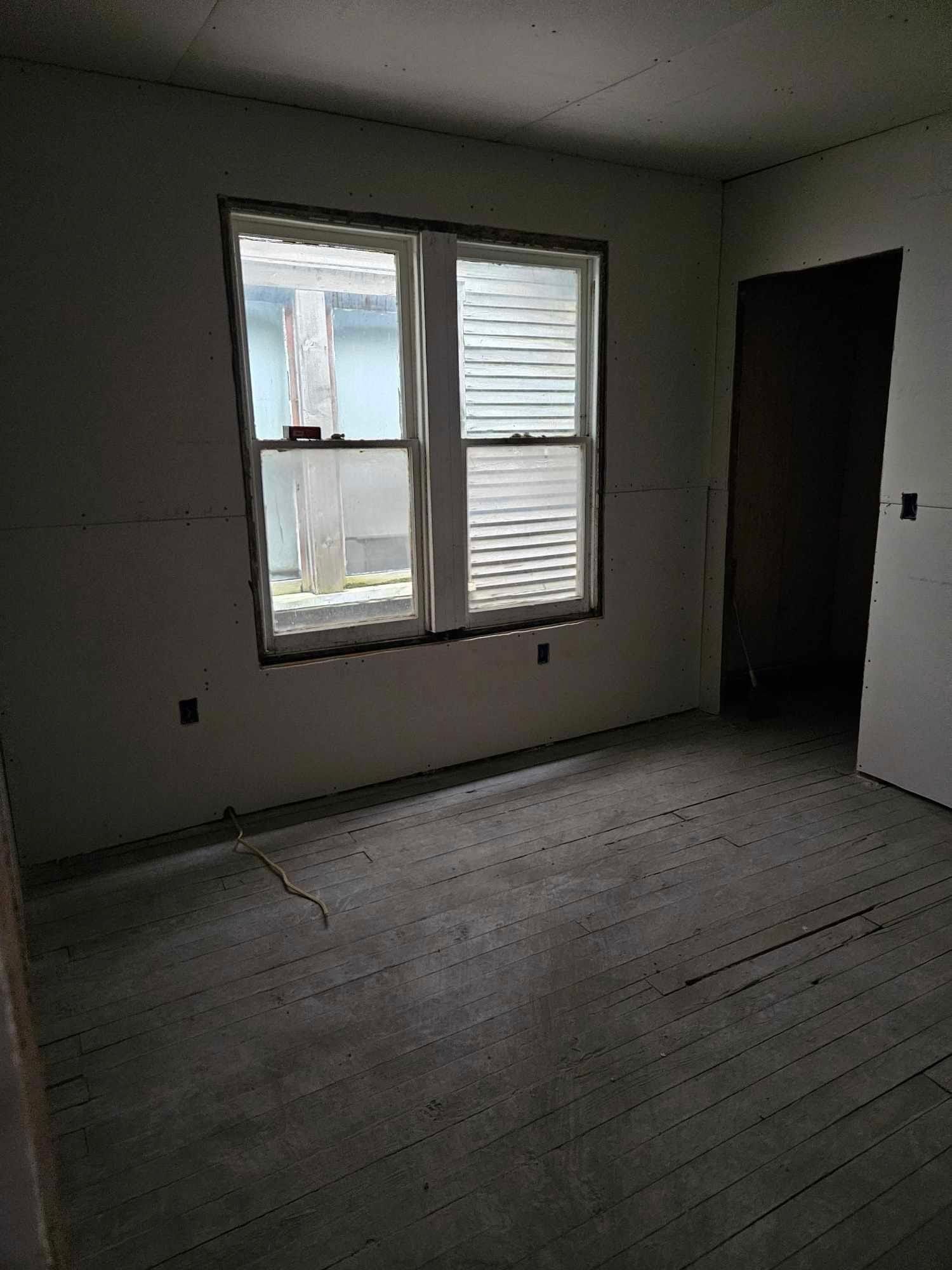 An empty room with two windows and a door.