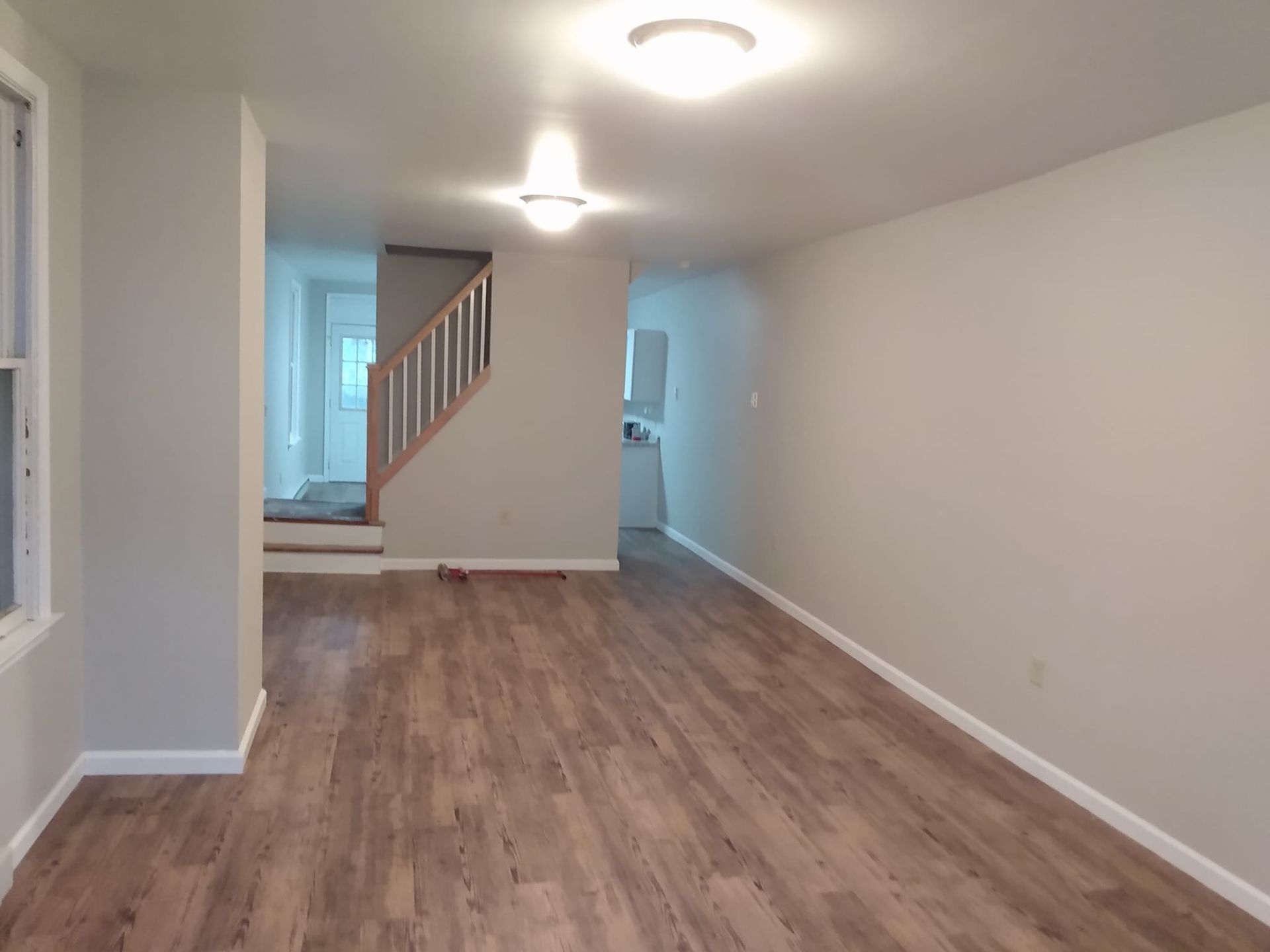 An empty living room with hardwood floors and white walls.
